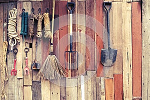 Agricultural tools hang on wooden wall in farm