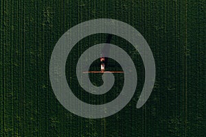 Agricultural tractor with crop sprayer applying fungicide treatment on wheat crops in spring, aerial view from drone pov