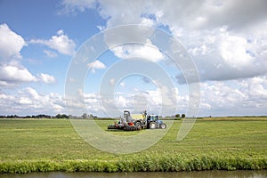 Agricultural tractor drives through field under a blue cloudy sky