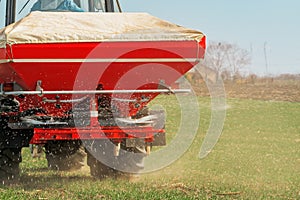 Agricultural tractor fertilizing wheat crop field with NPK