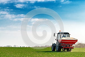 Agricultural tractor fertilizing wheat crop field with NPK