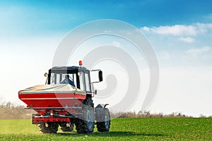 Agricultural tractor fertilizing wheat crop field with NPK