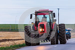 Agricultural tractor moving on the asphalt road after working in field