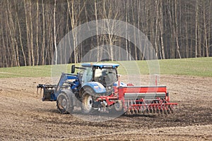 Agricultural tractor with seeder in the field, spring day