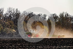 Agricultural tractor with seeder is working in the field