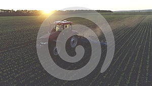 Agricultural tractor in the spring field on the sunset