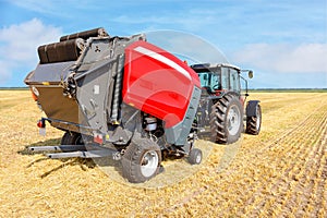 An agricultural tractor with a trailed unit for collecting straw from the field and storing it in bales