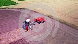Agricultural tractor with trailer for ploughing working on cultivated field