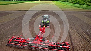 Agricultural tractor with trailer plowing on farming field. Agricultural sector