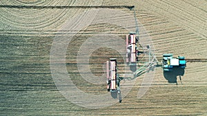 Agricultural vehicle is sowing the land in the field in a top view