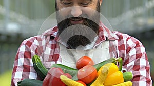 Agriculturalist smiling camera holding fresh vegetables in hands, harvesting