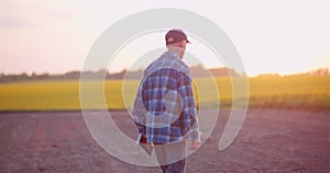 Agriculture - Farmer Walking on Field Examining Crops at Farm at Dusk.