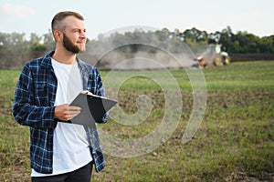 Agriculture. farmer working in a field in the background tractor plows ground in a field of wheat. farming agriculture