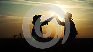 Agriculture farming two farmers men teamwork handshake red neck in a field examining wheat crop at sunset. male farmers