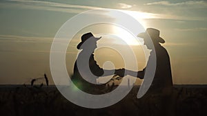 Agriculture farming two farmers men teamwork handshake red neck in a field examining wheat crop at sunset. Male farmers