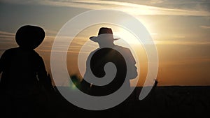 Agriculture farming two farmers men teamwork silhouette red neck in a field examining wheat crop at sunset. Male farmers