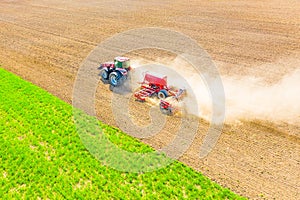 Agriculture on farmland. Red tractor ploughing soil in spring