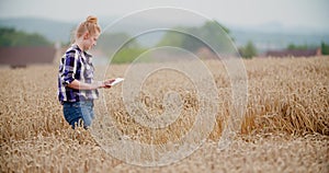 Agriculture female farmer walking in wheat field with digital tablet