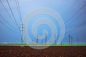 Agriculture field, electric posts, substation towers and industrial chimneys and factory