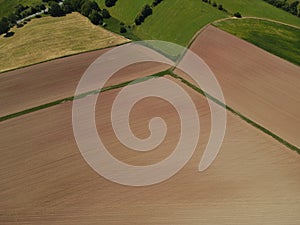 Agriculture fields with brown soil from above in summer