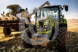 Agriculture industry machinery. Combine harvester and tractor with trailer unloading harvest. Farmer details