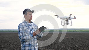 agriculture. smart farming tech farming. man farmer engineer studies a farmland in black mud dirt field using a