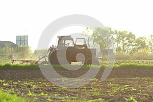 Agriculture. Tractor plowing field in sunset. Cultivated field. Agronomy, farming, husbandry