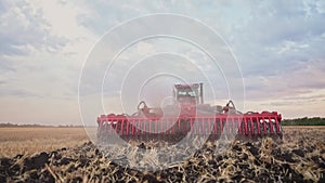 Agriculture. tractor plows a field of black soil against the background of blue clouds. agriculture business industry