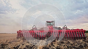 Agriculture. tractor plows a field of black soil against the background of blue clouds. agriculture business industry