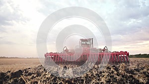 Agriculture. tractor plows a field of black soil against the background of blue clouds. agriculture business industry
