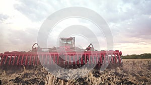 Agriculture. tractor plows a field of black soil against the background of blue clouds. agriculture business industry