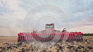 Agriculture. tractor plows a field of black soil against the background of blue clouds. agriculture business industry