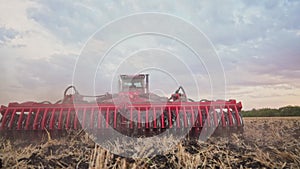 Agriculture. tractor plows a field of black soil against the background of blue clouds. agriculture business industry