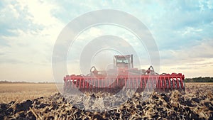 Agriculture. Tractor plows a field of black soil against the background of blue clouds. Agriculture lifestyle business