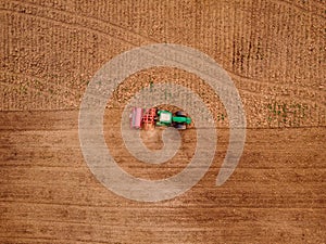 Agriculture tractor plows field of land for sowing. Top view aerial photo.