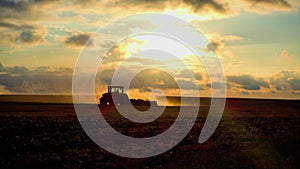 Agriculture. Tractor plows the field at sunset. Land cultivation after wheat harvest.