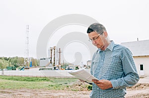 agriculture worker using tablet in front of grain silos outdoors