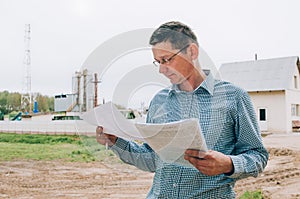 agriculture worker using tablet in front of grain silos outdoors