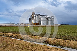 agro-industrial complex with silos and a seed cleaning and drying line for grain storage in snow of winter field