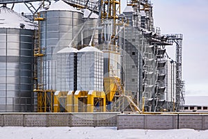 agro-industrial complex with silos and a seed cleaning and drying line for grain storage in snow of winter field
