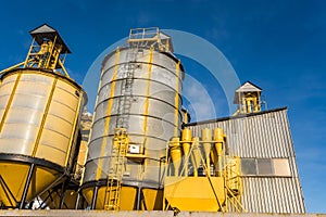 Agro silos granary elevator in winter day in snowy field. Silos on agro-processing manufacturing plant for processing drying