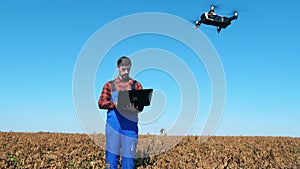 Agronomist controls a drone while standing on a farmfield.