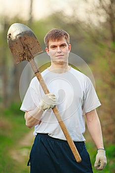 Agronomist handsome strong man with shovel on background of flo