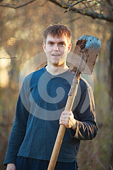 Agronomist handsome strong man with shovel on background of flo