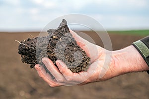 Agronomist holding a clod of earth, closeup of male hand with soil sample from agricultural field photo
