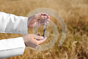 Agronomist holding test tube with soil sample in field. Cereal farming