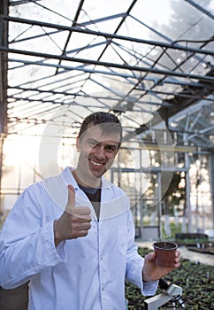 Agronomist showing thumb up and sprout in greenhouse