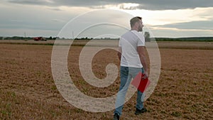 Agronomist in white t-shirt and jeans walking in wheat field.