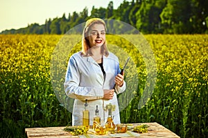 Agronomist woman or farmer examine rapeseed oil using tablet on the background of  blossoming rape canola field