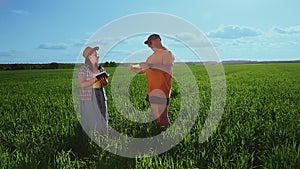 Agronomists a man and a woman in a field inspect crops of crops and record observations